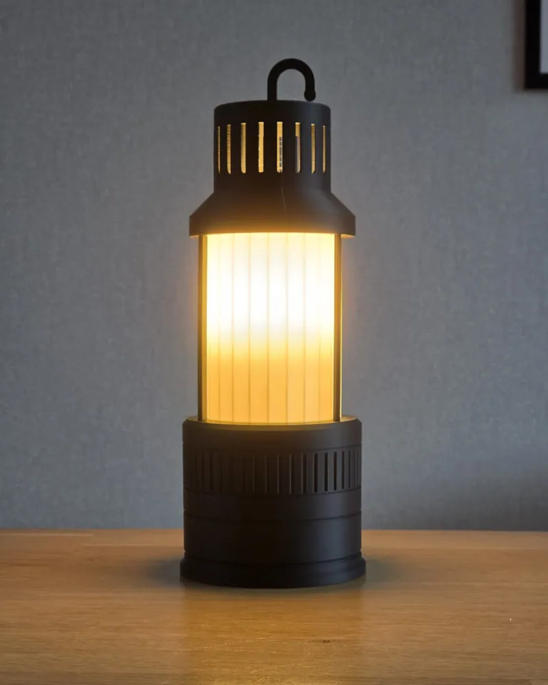 Brandende 3D-geprinte mijnwerkerslamp in steenkoolzwart met matwitte kap op een houten tafel